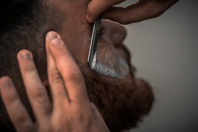 A barber shaving beards of a man