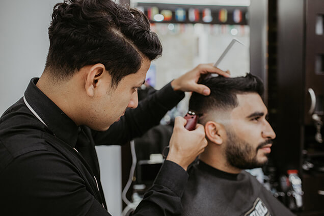 a barber styling the hairstyle of a man using trimmer