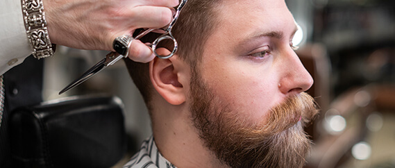 a barber is styling a bearded man hairstyle